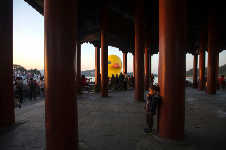 A boy plays in Chinese traditional pavilion next to an inflated Rubber Duck in Beijing