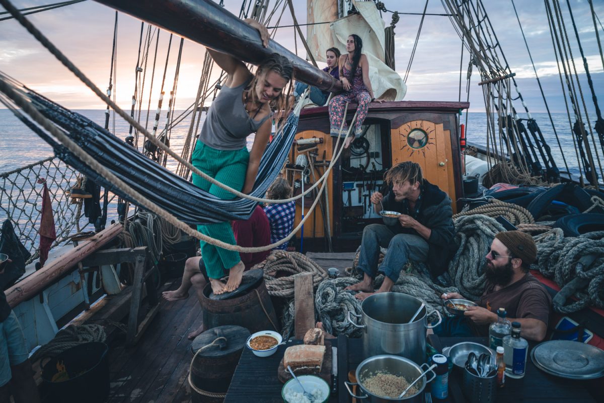Une partie de l'équipage du voilier Tres Hombres mange sur le pont.